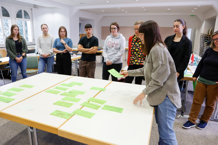 Studierende stehen um einen tisch herum
